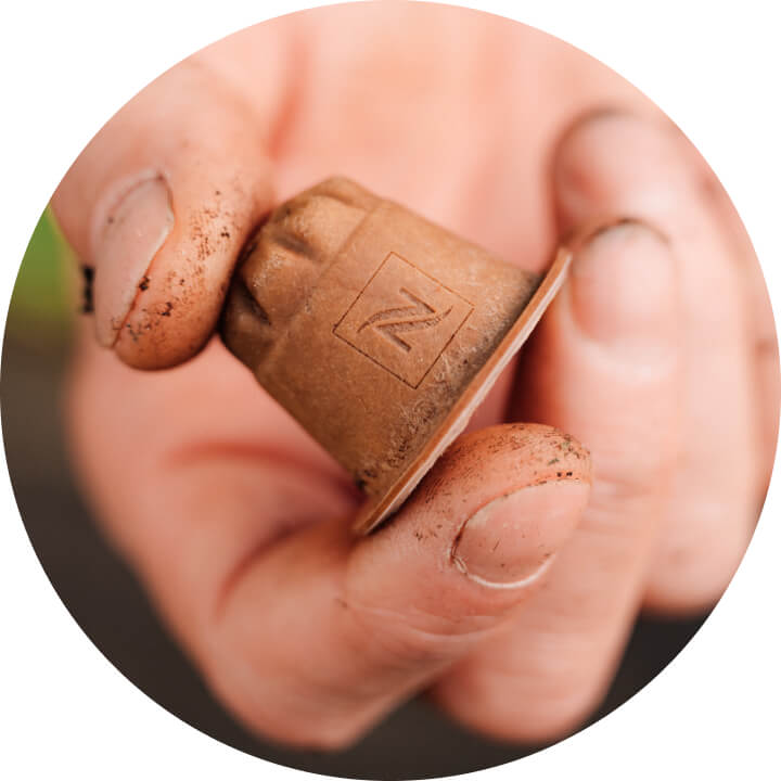 Nespresso Home Compostable koffiecapsule in de hand van een koffieboer