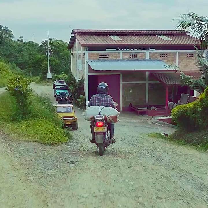 Person on motorcycle delivering coffee beans to a coffee mill